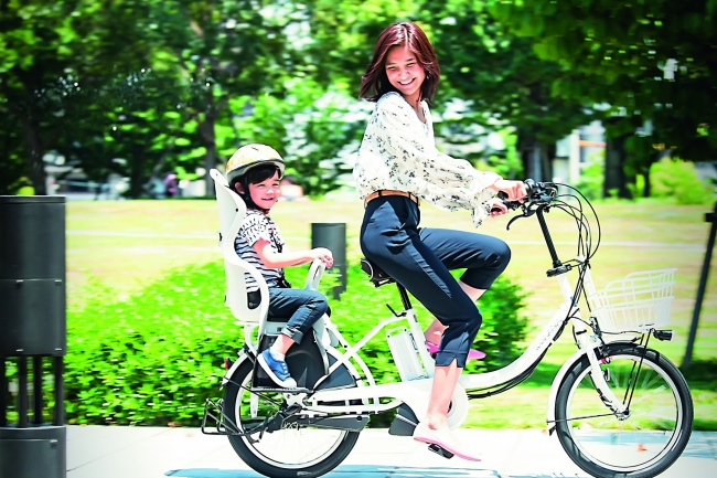 子どもを後ろに乗せて電動アシスト自転車に乗るママ