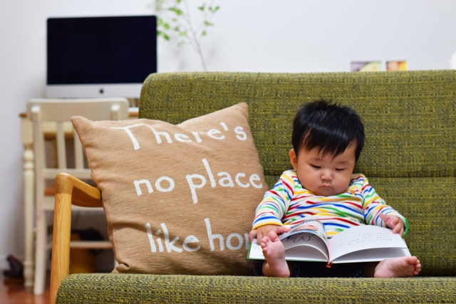 ソファに座って絵本を読む赤ちゃん