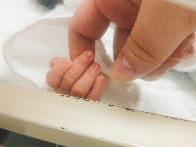 生まれたばかりの赤ちゃんの小さな手をさわる指
