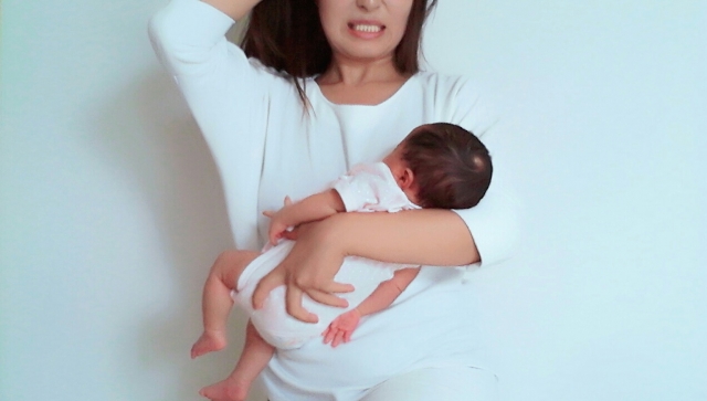 赤ちゃんを抱っこしながらイライラしているママ