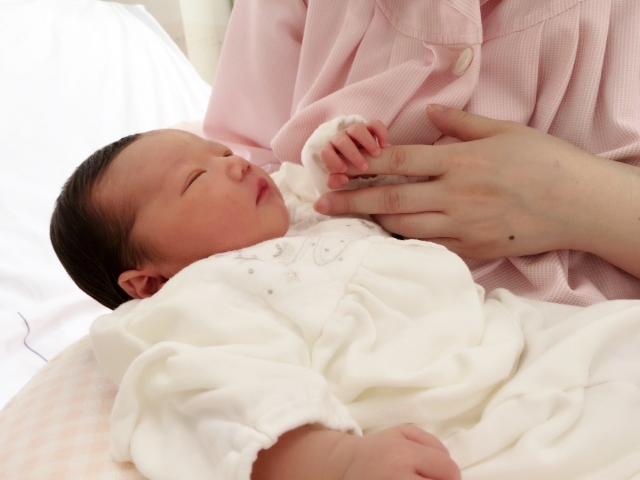 生まれたばかりの赤ちゃんの手をとるママ