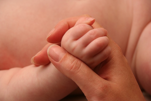 小さな赤ちゃんの手を握るママの手
